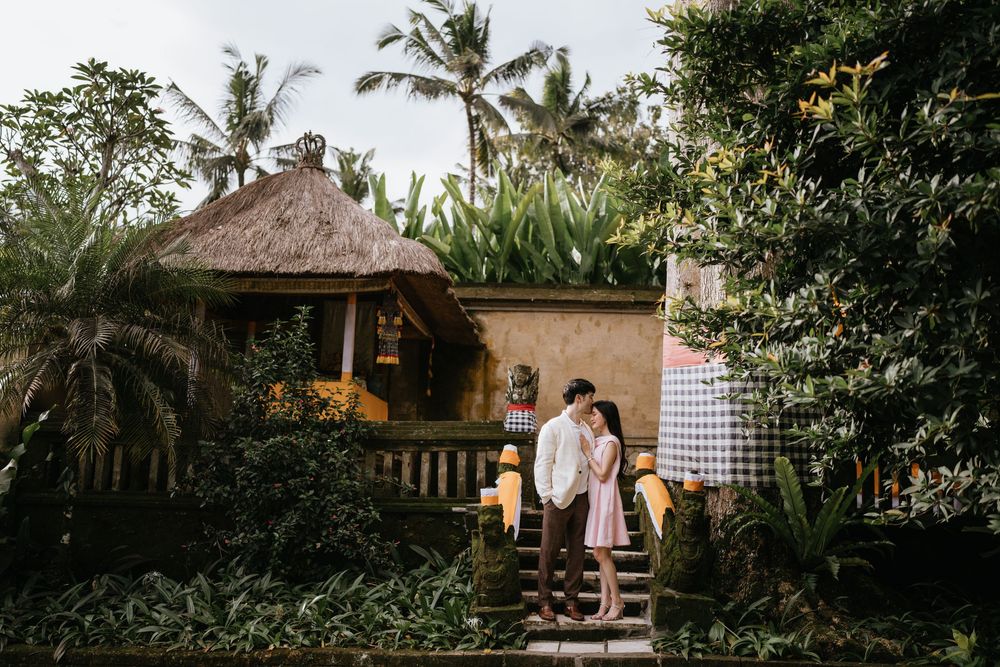 A tranquil garden pathway lined with tropical foliage and traditional Balinese architecture.