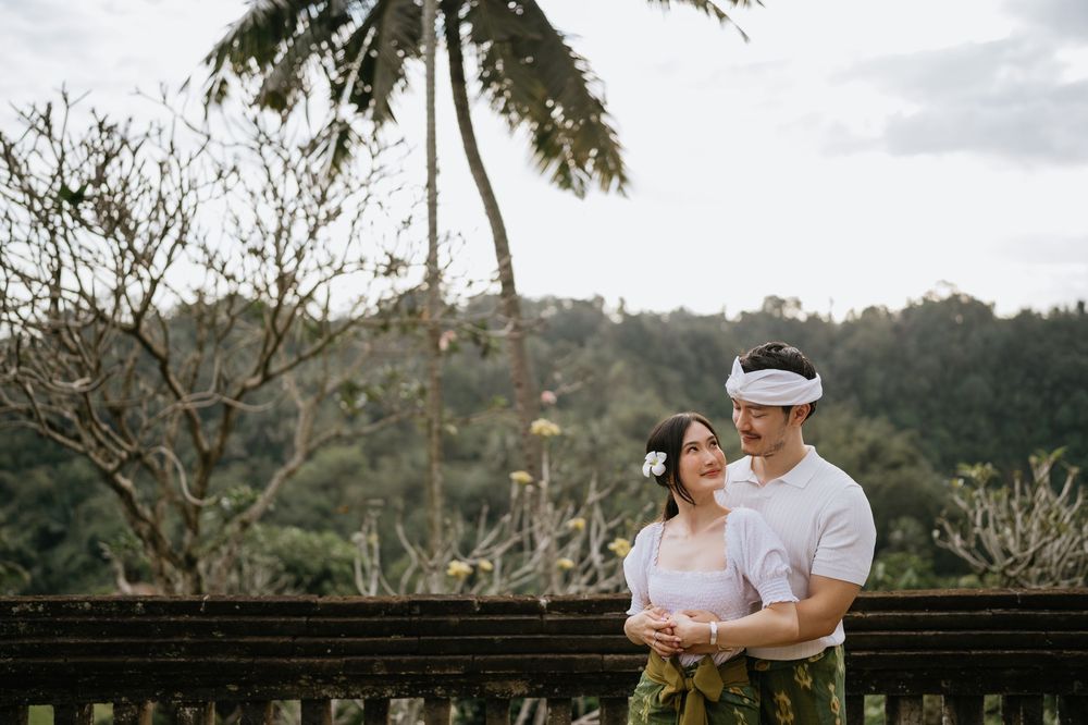 A couple shares tender moments in a tropical garden setting with palm trees.