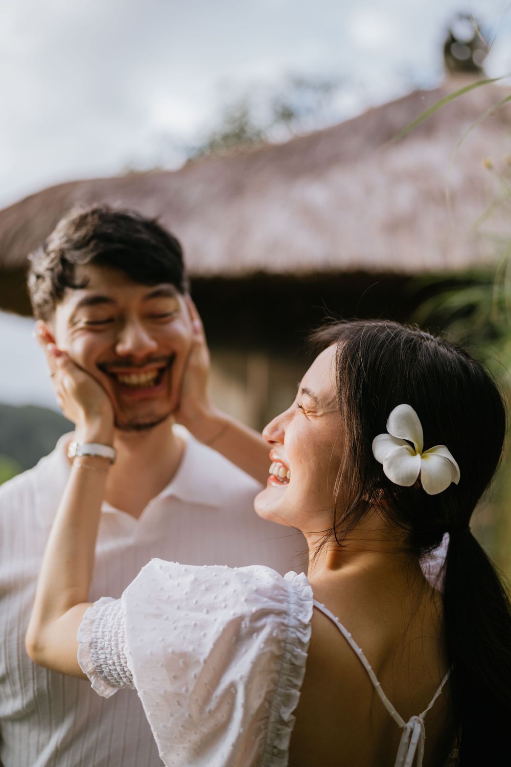 A joyful couple shares laughter while wearing traditional Balinese attire.