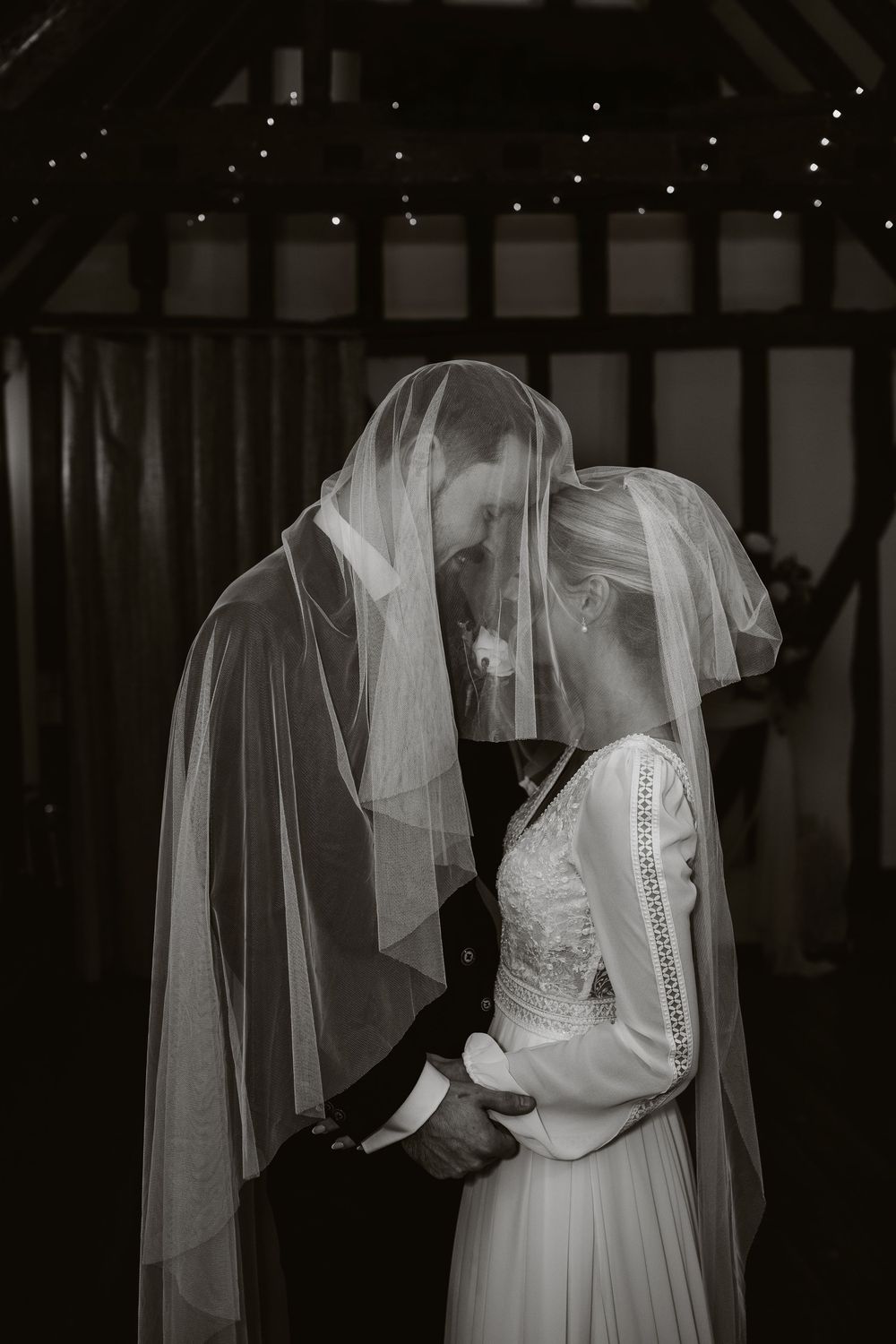 A series of black and white photos showing details of a bride's lace wedding dress and flowing veil.