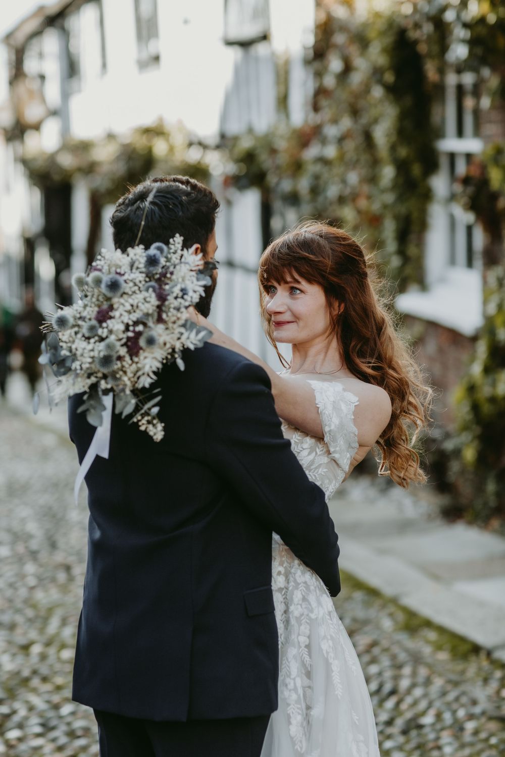 A romantic wedding photo series showing a couple dancing together in a lace dress and dark suit outdoors. The George in Rye