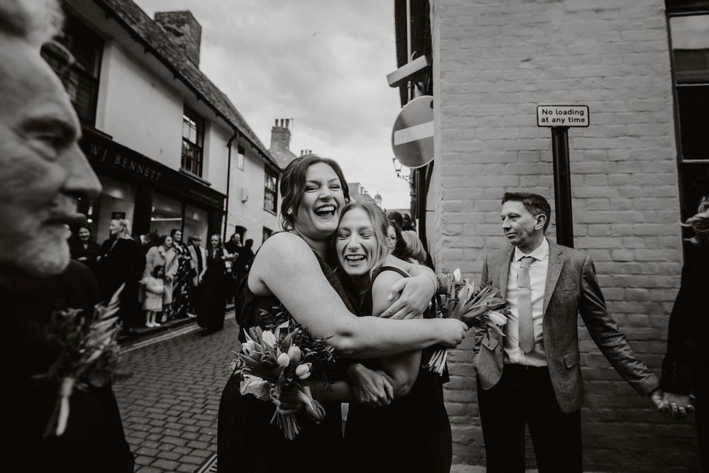 Black and white candid wedding photographs showing guests celebrating and interacting at an outdoor reception.