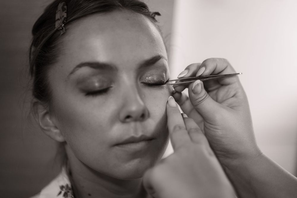 Close-up shots of makeup application during bridal preparation in black and white.