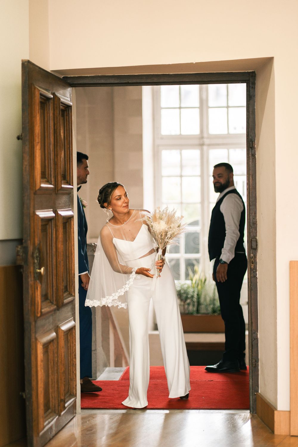 Wedding party preparing in elegant hallway with natural lighting.