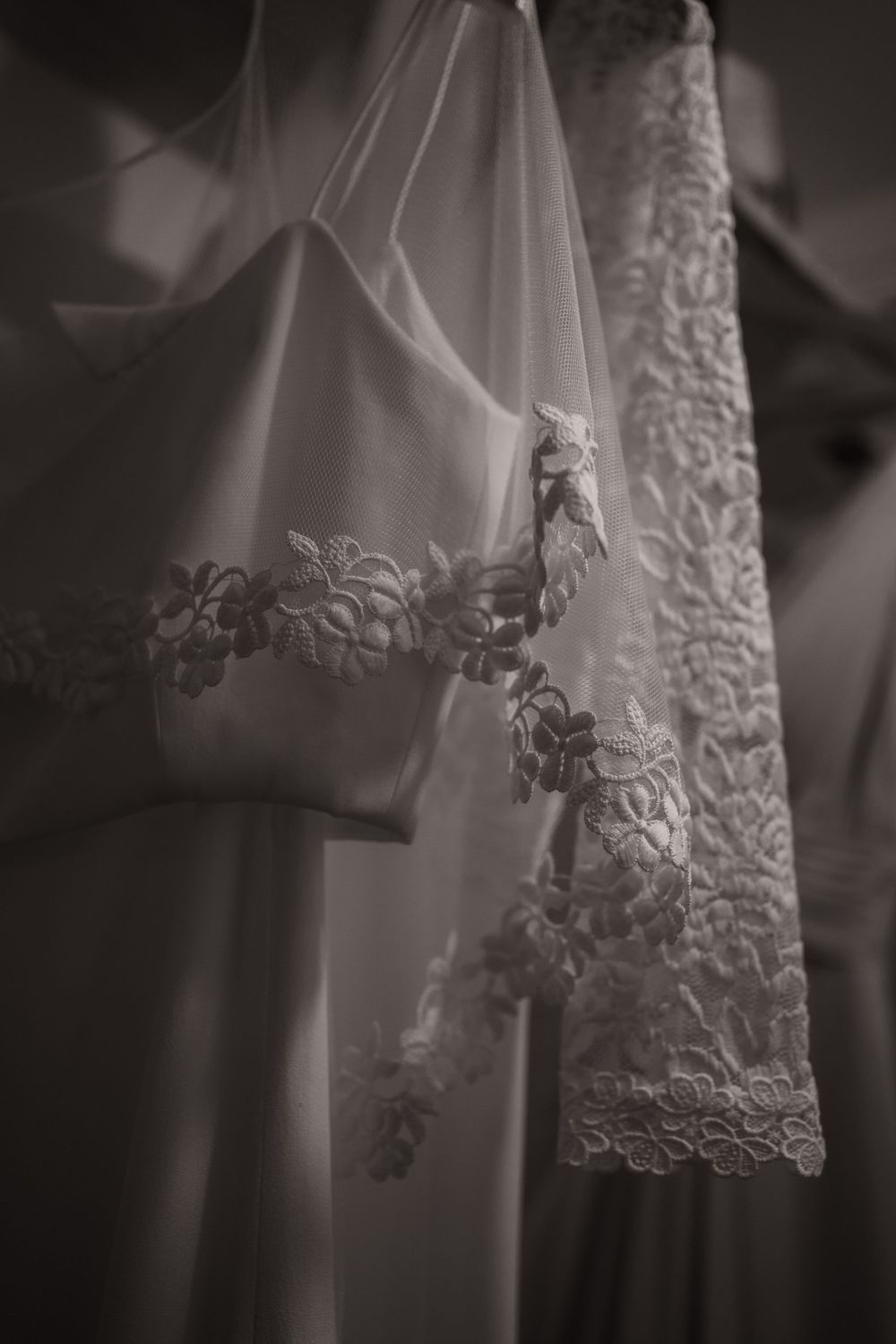 Close-up detail of delicate lace embroidery on a white wedding dress veil in black and white.