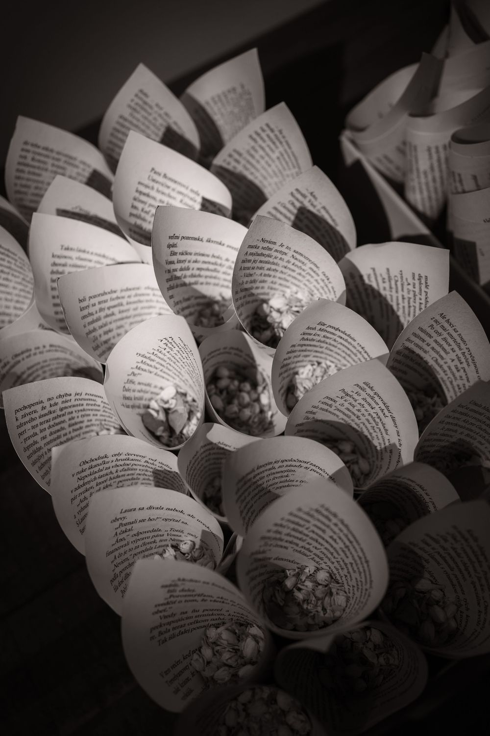 Black and white image of paper wedding programs or confetti cones arranged artistically.