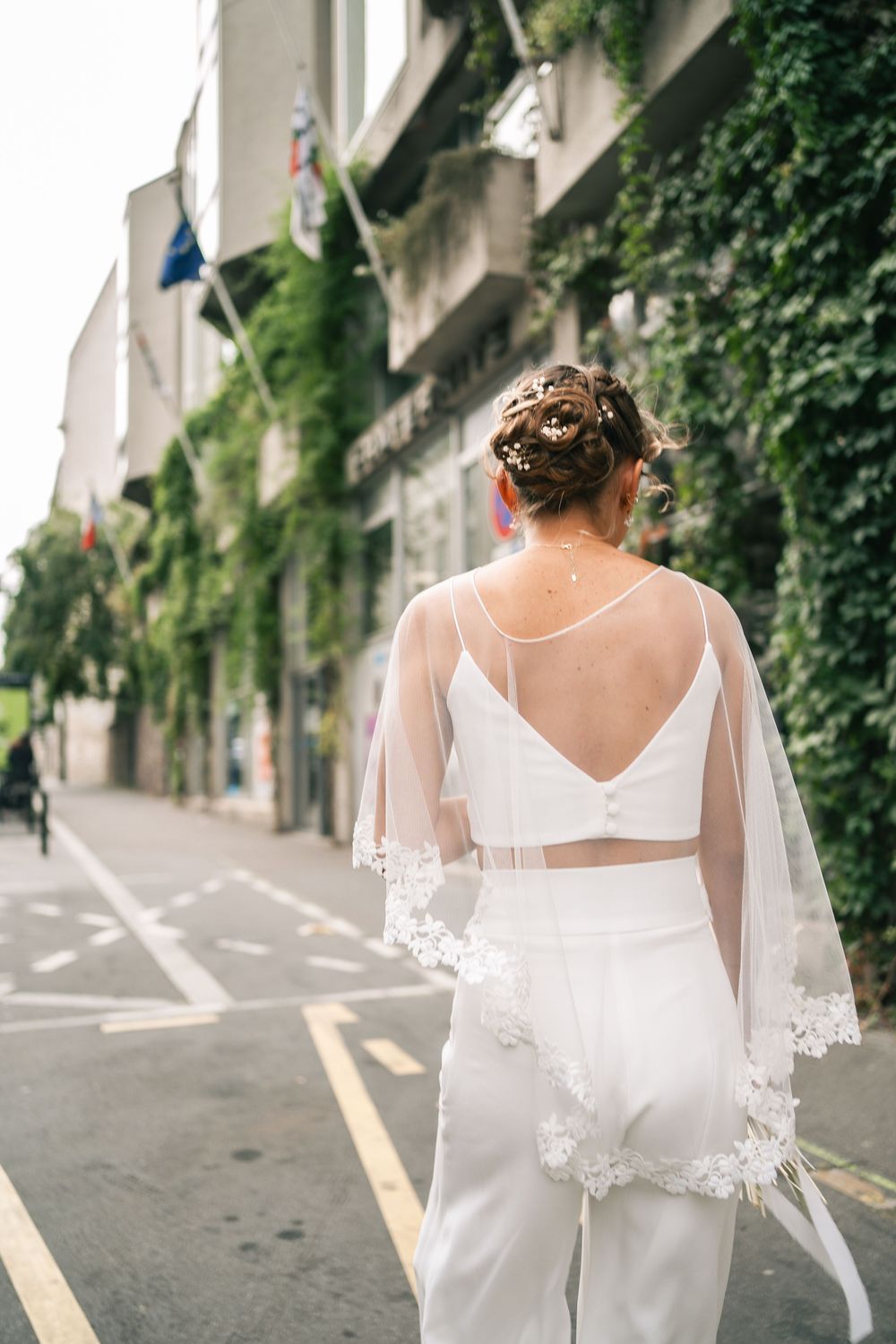 Artistic back view of wedding dress details with lace sleeves on city street.