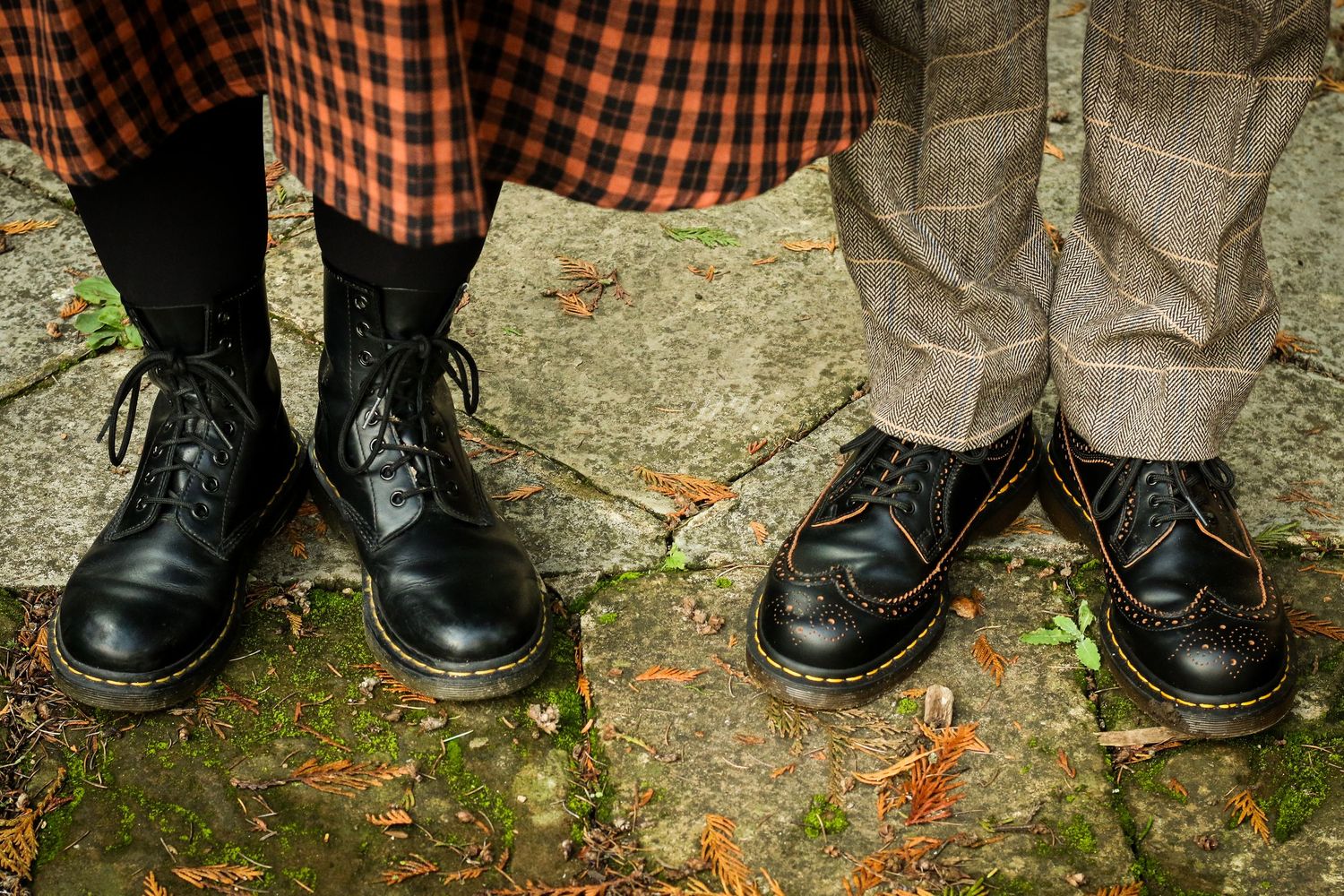 Black leather boots and orange plaid socks shown in detail against a natural outdoor background.