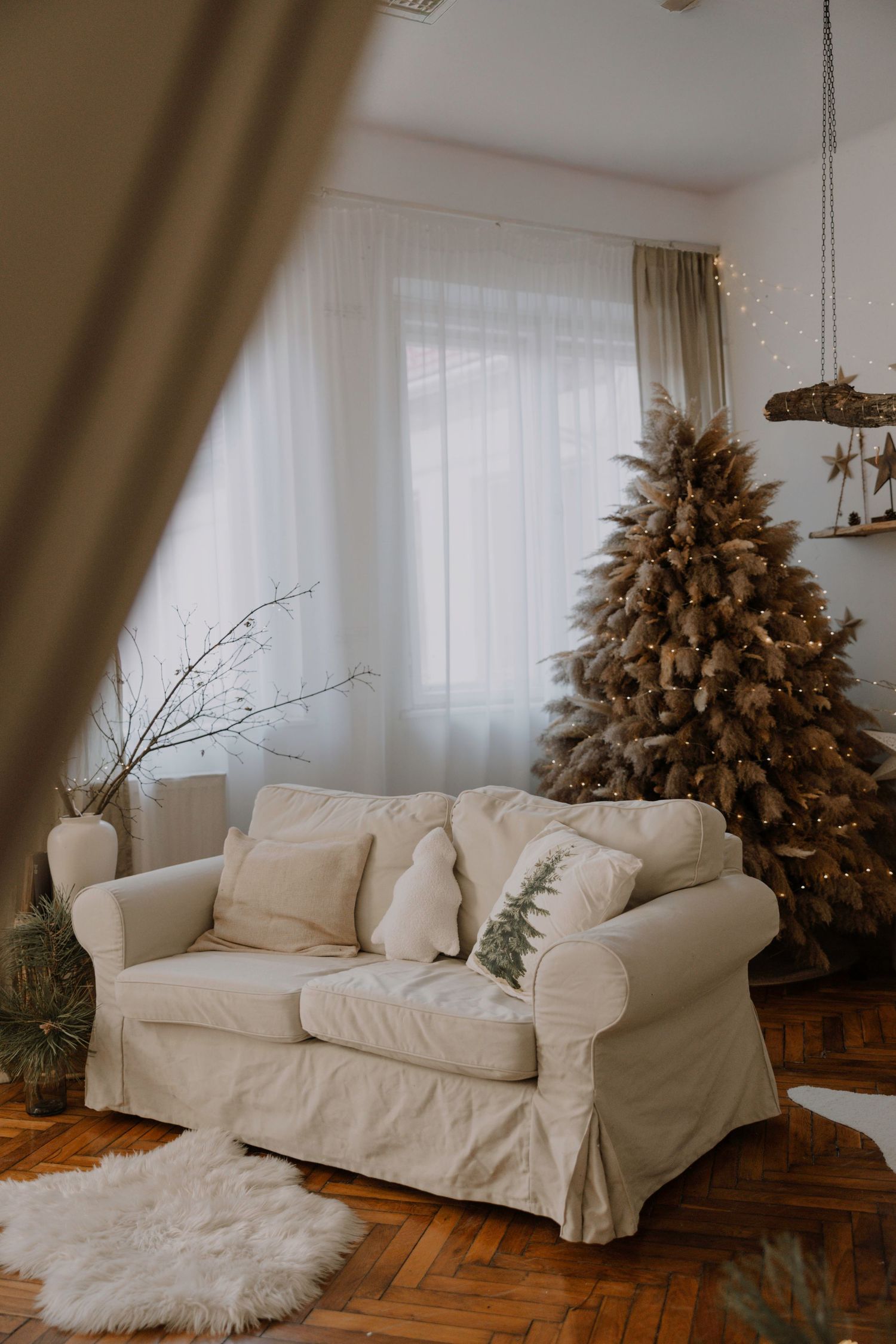 White slipcovered sofa with cozy sheepskin rug and dried floral arrangement in a bright, minimalist living room.