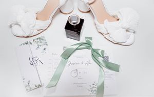 Wedding invitation suite featuring delicate white stationery with sage green ribbon accents.