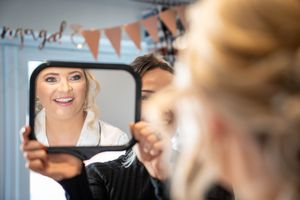 Wedding preparations showing makeup application and getting ready moments in a brightly lit room.