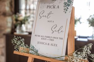 Rustic wedding signage and seating cards decorated with eucalyptus leaves and elegant calligraphy.
