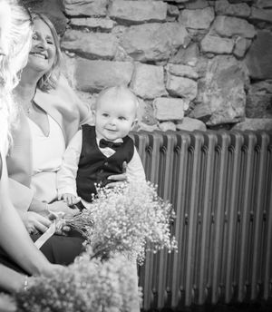 Black and white candid moments from a wedding celebration with rustic stone wall backdrop.