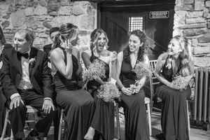 Wedding party sitting on stone steps while enjoying candid moments during the celebration.