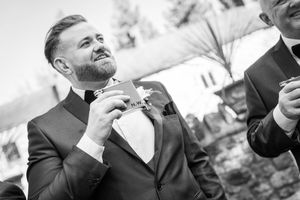 Black and white shot of groomsmen laughing together during wedding celebration.