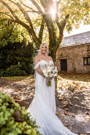 Wedding photography in golden sunlight with stone building and autumn leaves creating magical atmosphere.