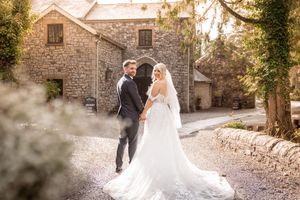 Sun-drenched autumn wedding portraits at rustic stone venue with ivy-covered walls.