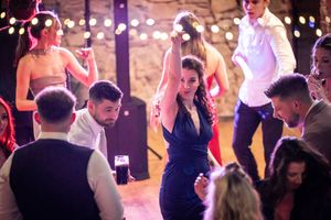 Guests enjoying a lively dance party at a wedding reception with twinkling lights and stone walls creating an intimate atmosphere.