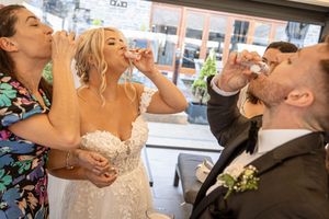 A couple raising their champagne glasses during an elegant wedding celebration at an indoor venue.