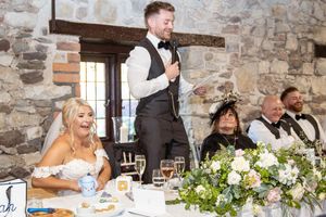 Wedding guests seated at a rustic stone-walled venue celebrate during the wedding reception.