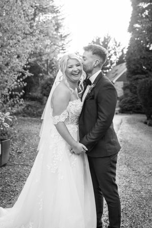 A couple shares a joyful moment together outdoors surrounded by autumn trees and fallen leaves.