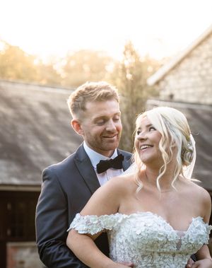 Romantic sunset portrait of newlyweds sharing a joyful moment outdoors.