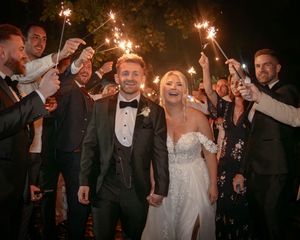 Wedding guests celebrate with sparklers creating a magical nighttime atmosphere.