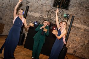 Wedding party dancing and celebrating in a rustic brick-walled reception venue.