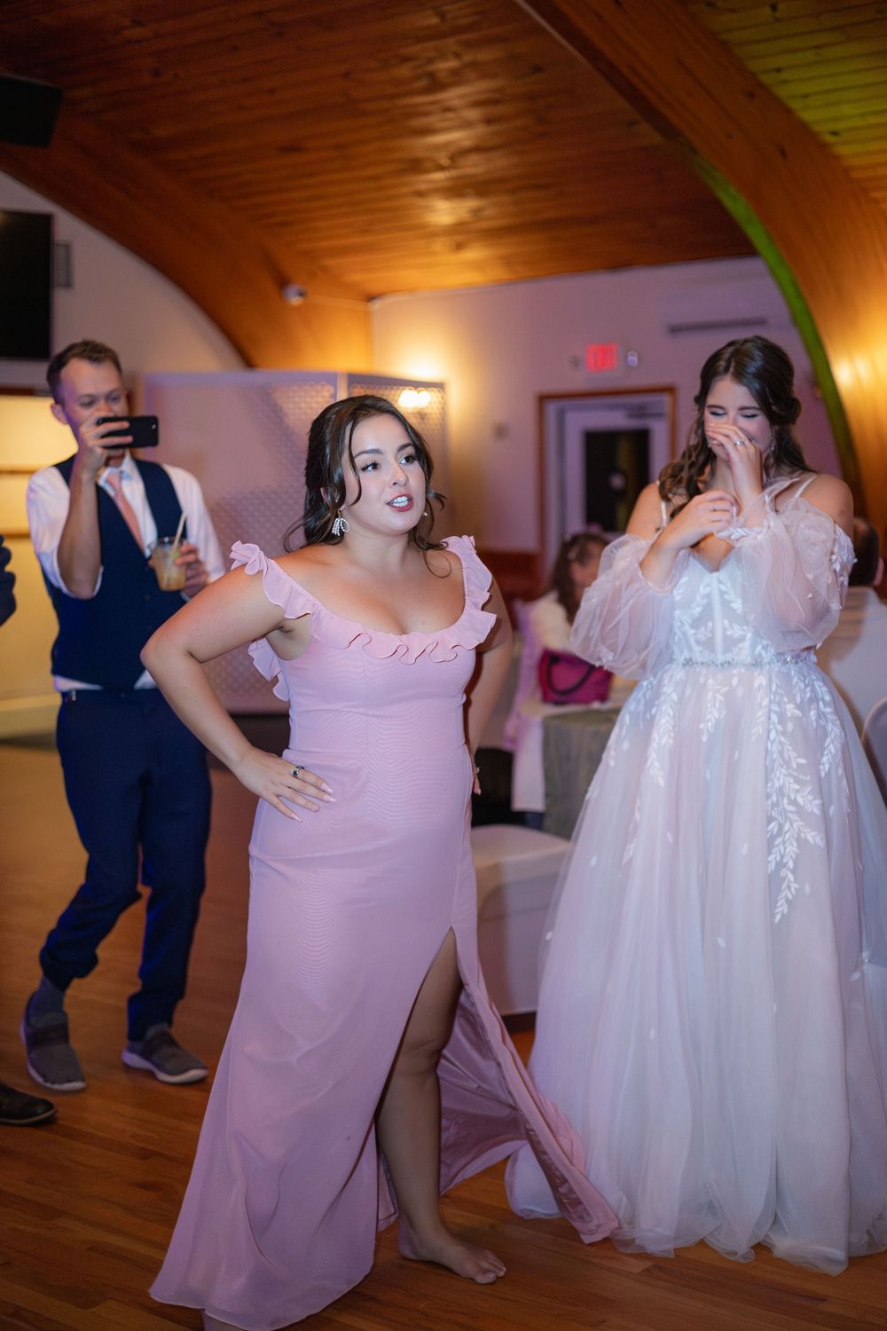 Candid dance floor moments at a wedding reception with dancers in pink and white formal attire.