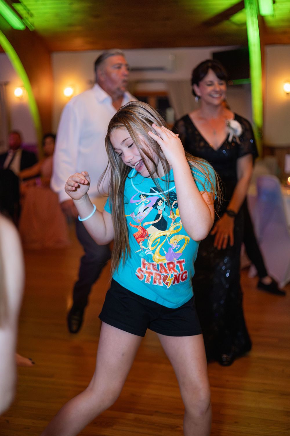 Energetic dancers in bright blue shirts move to the music on a wooden dance floor.