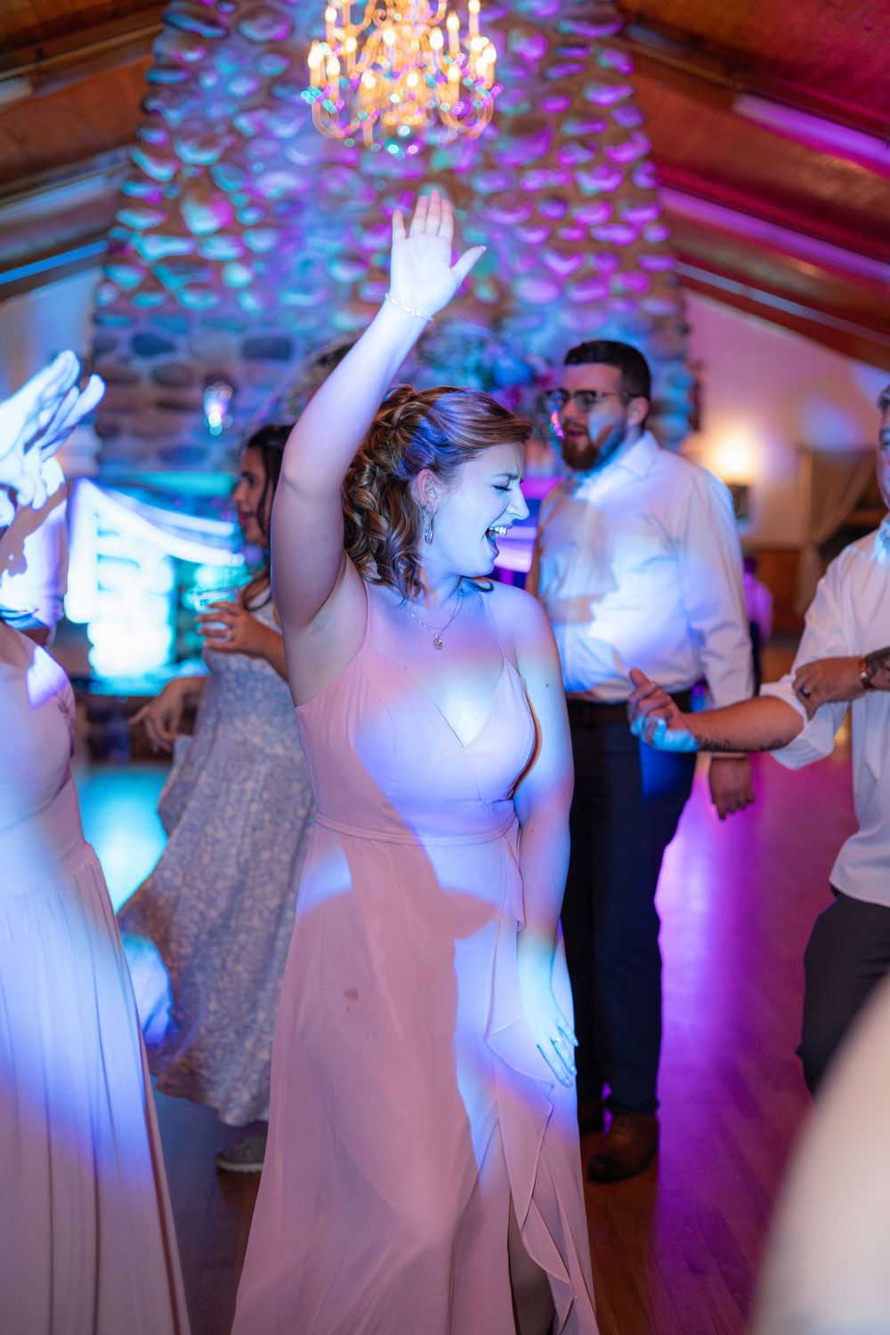 Wedding reception dance floor scene with colorful lighting and dancers in white dresses.