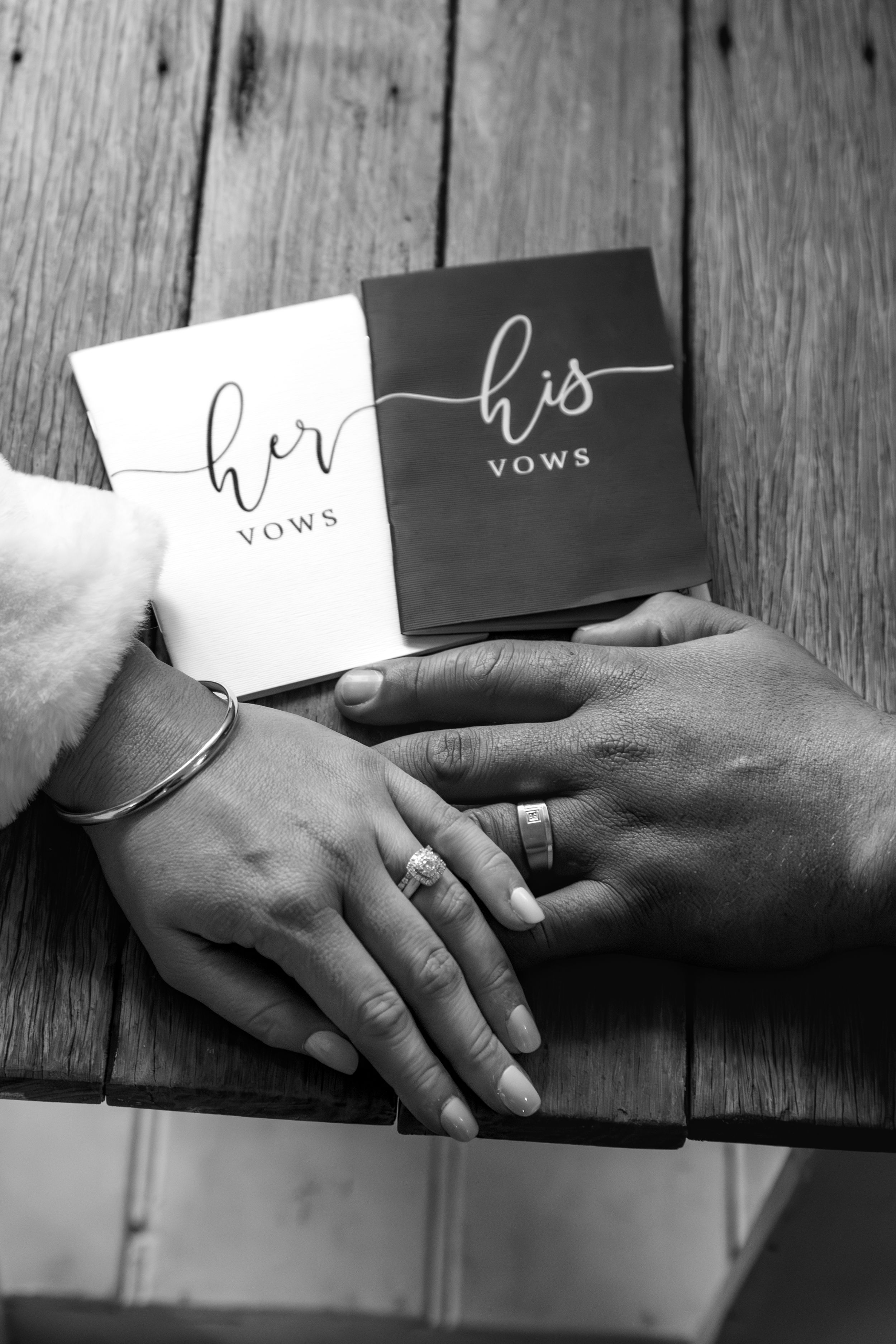 Black and white photo series showing hands exchanging vow cards against rustic wooden background.