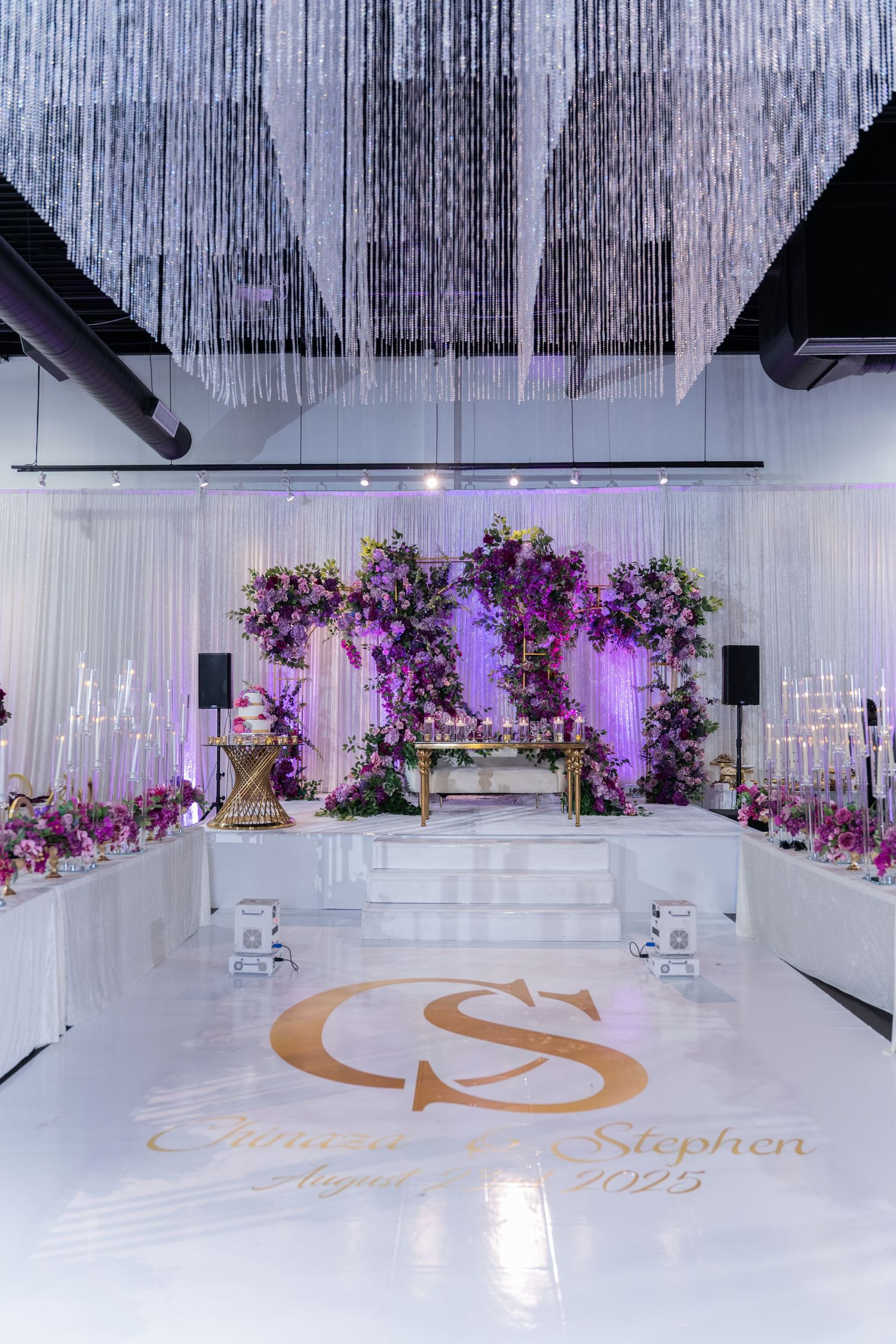 Elegant white reception hall with purple lighting and floral decorations.