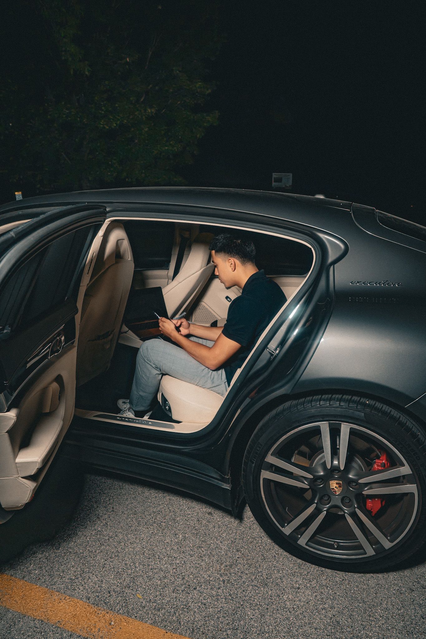 Low-angle view of a luxury black car with multiple door shots showing tan leather interior and black wheels.