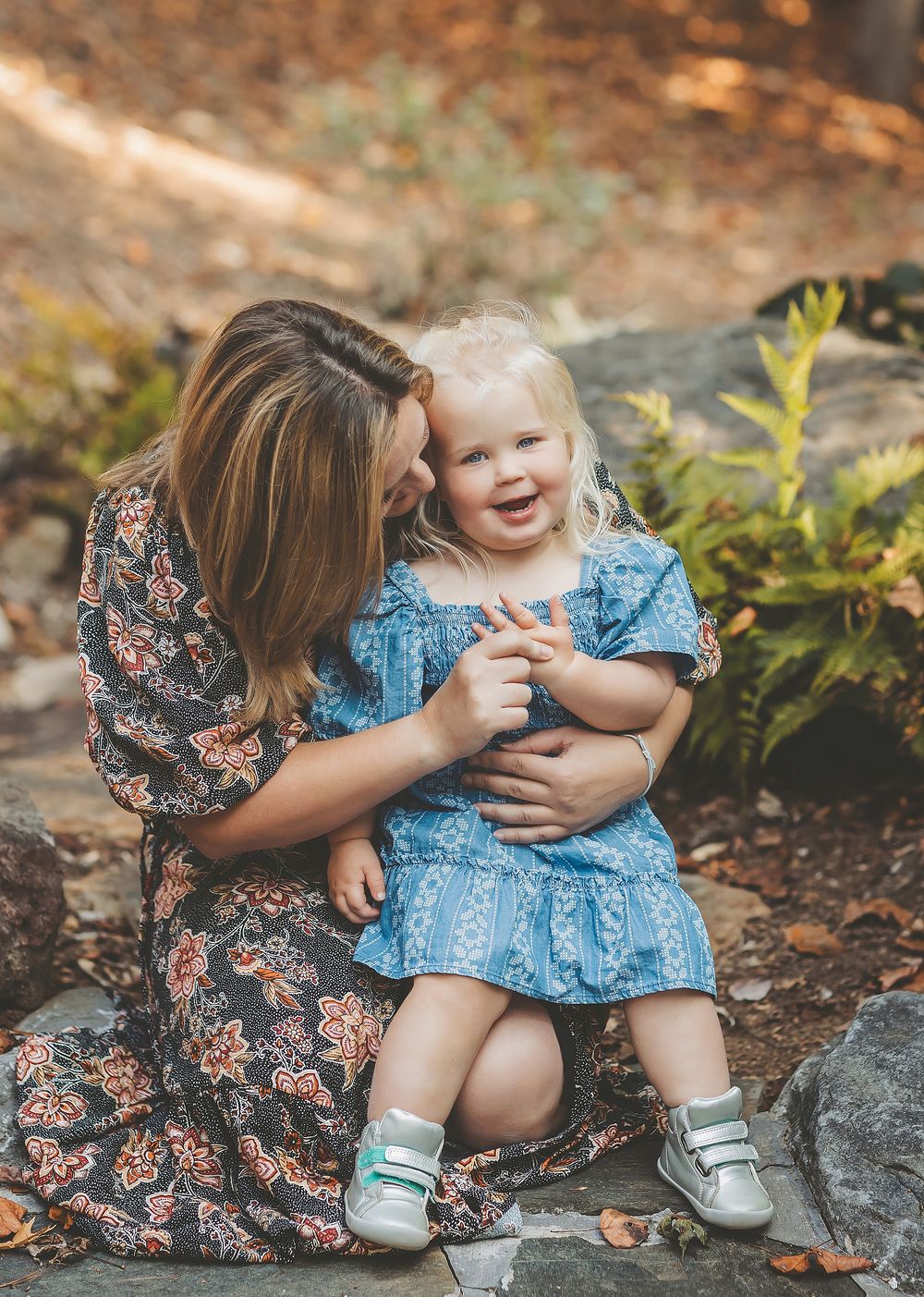 A heartwarming outdoor photo series showing tender moments between parent and child in blue dresses against a natural backdrop.