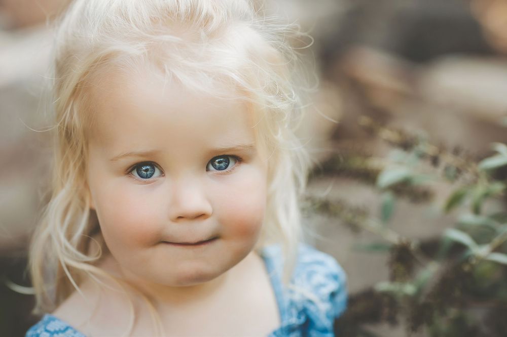 A series of seven close-up photos showing a young child with blonde hair and blue eyes in various candid expressions.