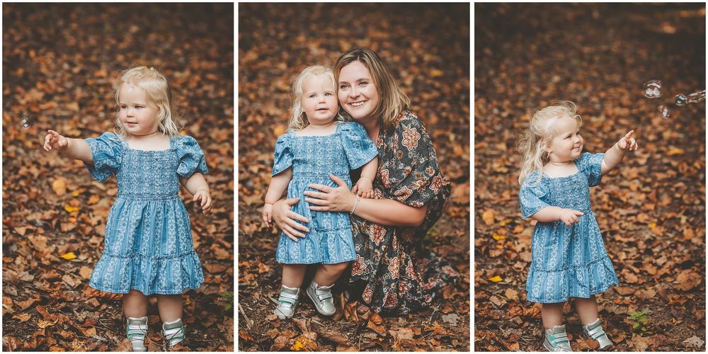 A child in a blue dress plays and poses among fallen autumn leaves during an outdoor photo session.