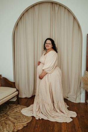 A series of artistic photos showing a figure draped in cream colored fabric against a neutral backdrop on hardwood floors.