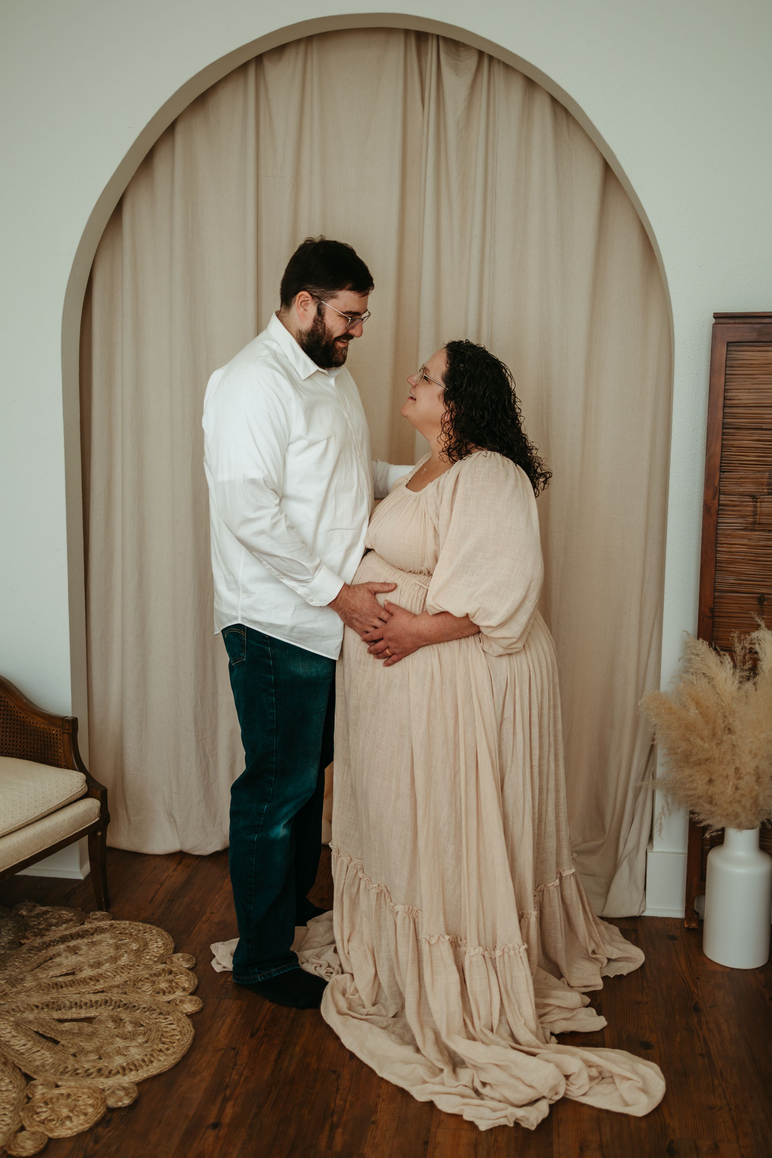 A couple in white and beige attire share an intimate moment during a romantic photoshoot sequence on hardwood floors.