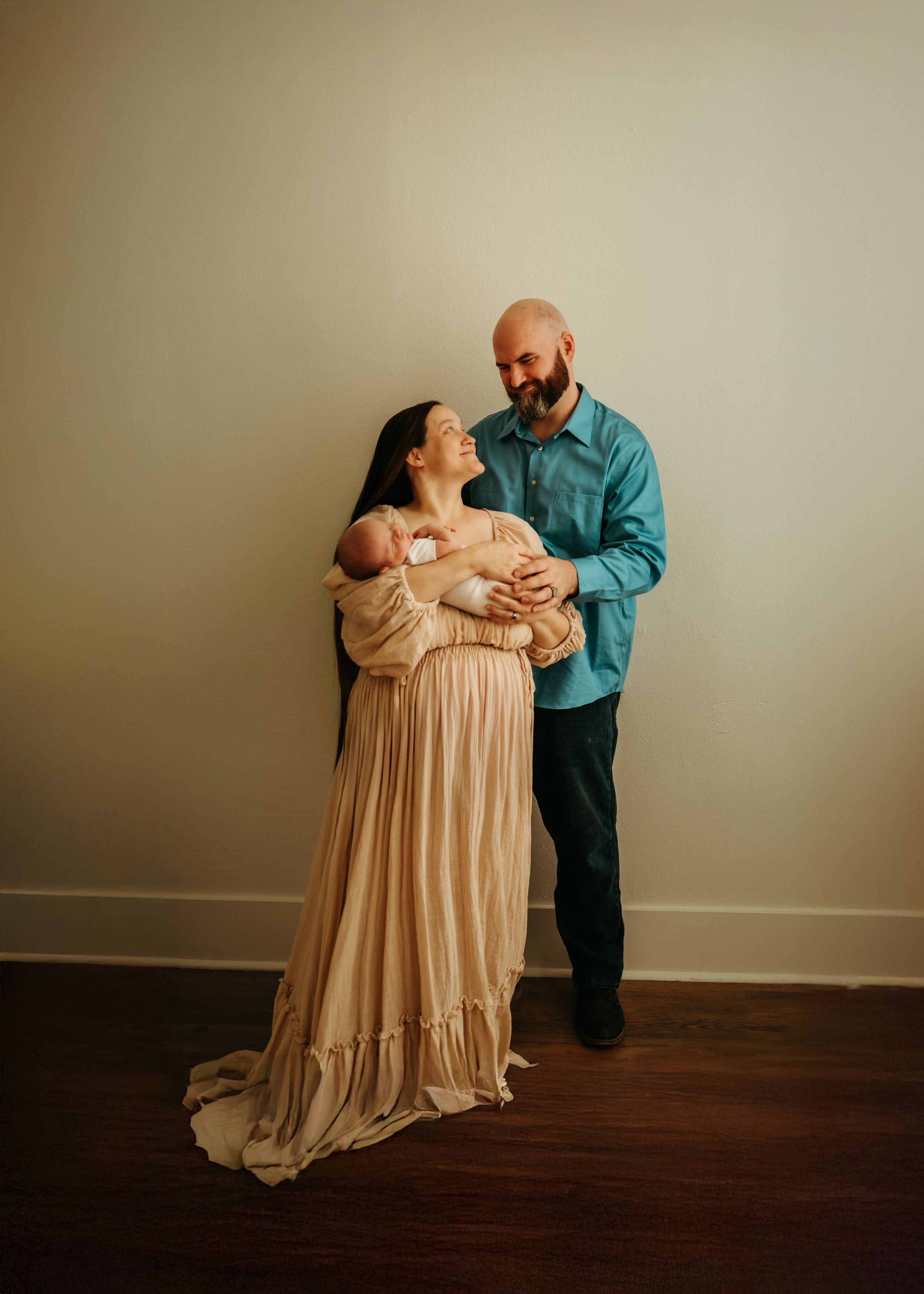 A series of five progressive photos showing a parent in a teal shirt lifting and cradling a baby in a flowing beige dress.