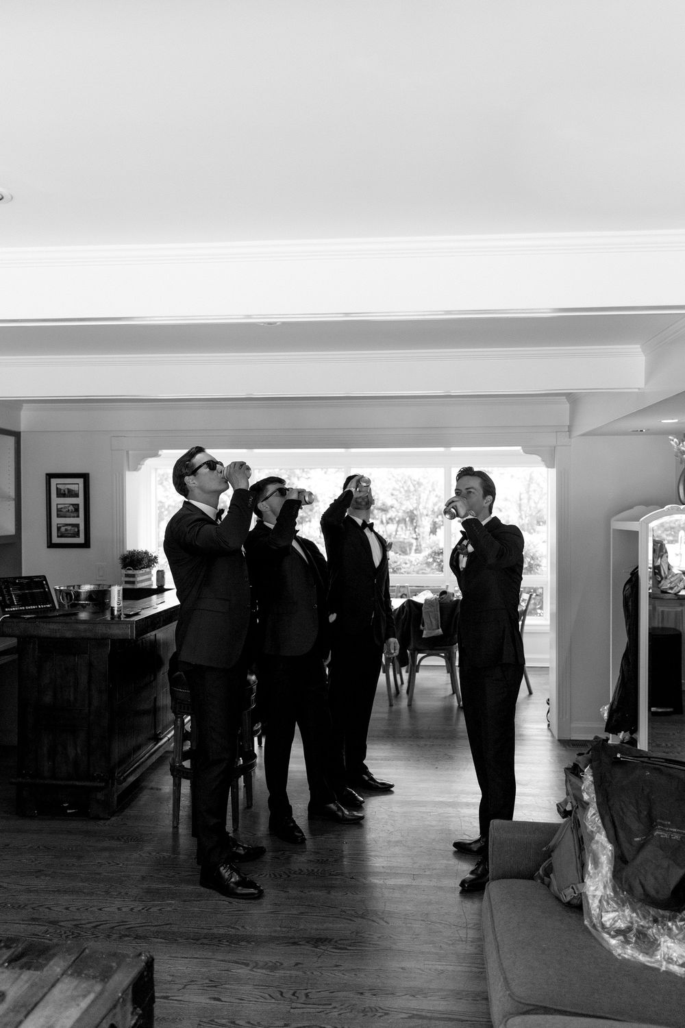 A black and white panoramic image shows people standing in a gallery-like space with white walls.