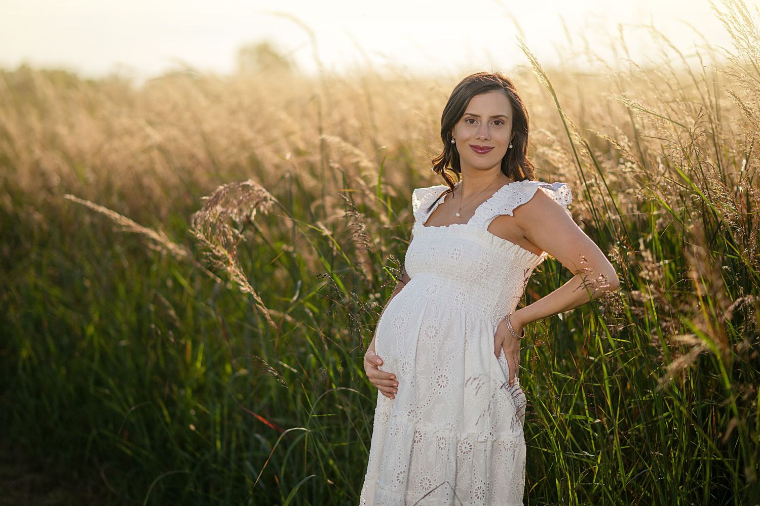 A couple shares a tender moment in a sunlit field of tall grass during golden hour.