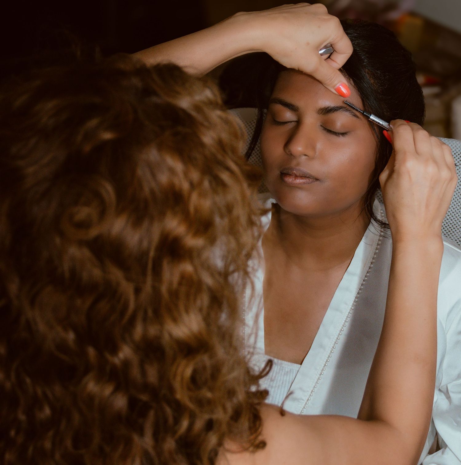 Professional makeup application in warm lighting during wedding preparation.