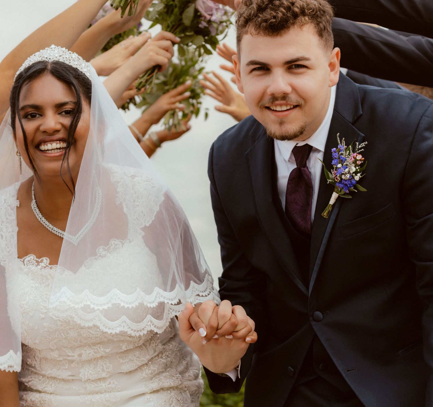 Joyful newly married couple holding hands and celebrating during outdoor wedding ceremony.