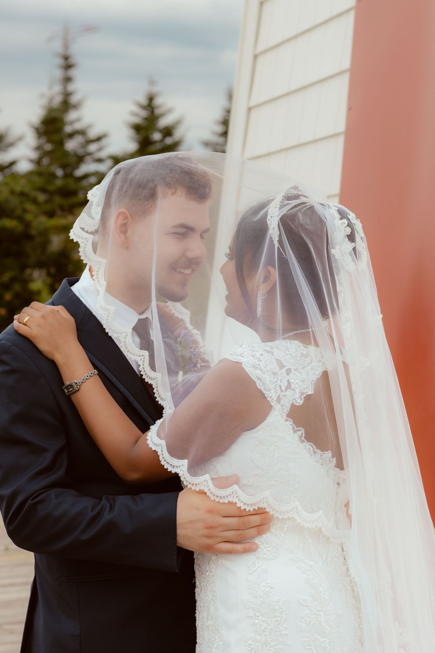 Couple shares intimate moment near lighthouse during wedding celebration.