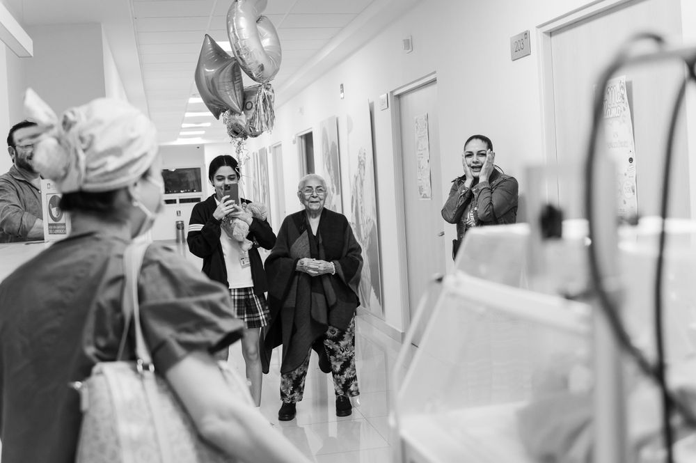 Hospital staff walking through bright medical facility hallway.