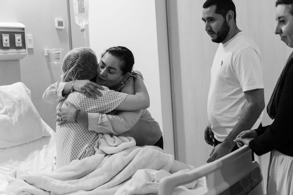 Medical staff and family members interacting in hospital room setting.