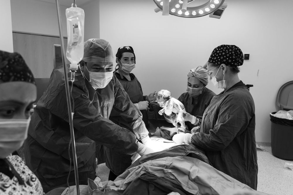 Medical team in surgical attire performing a cesarean section procedure in a hospital operating room.