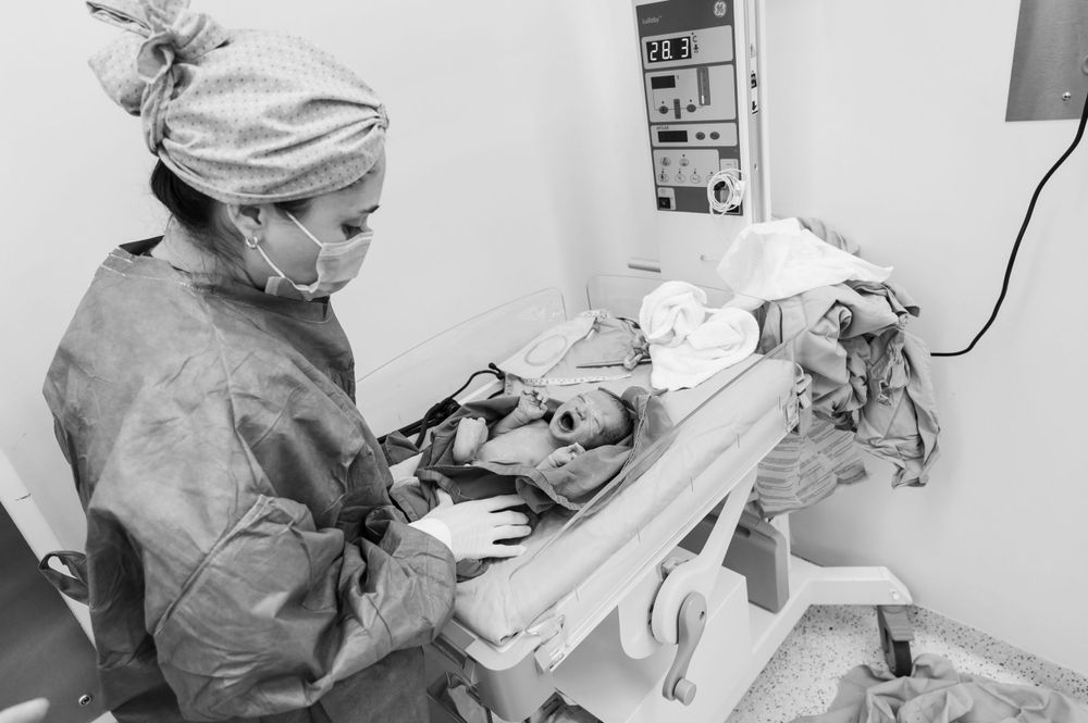 Medical staff performing surgery while wearing protective equipment and surgical masks.