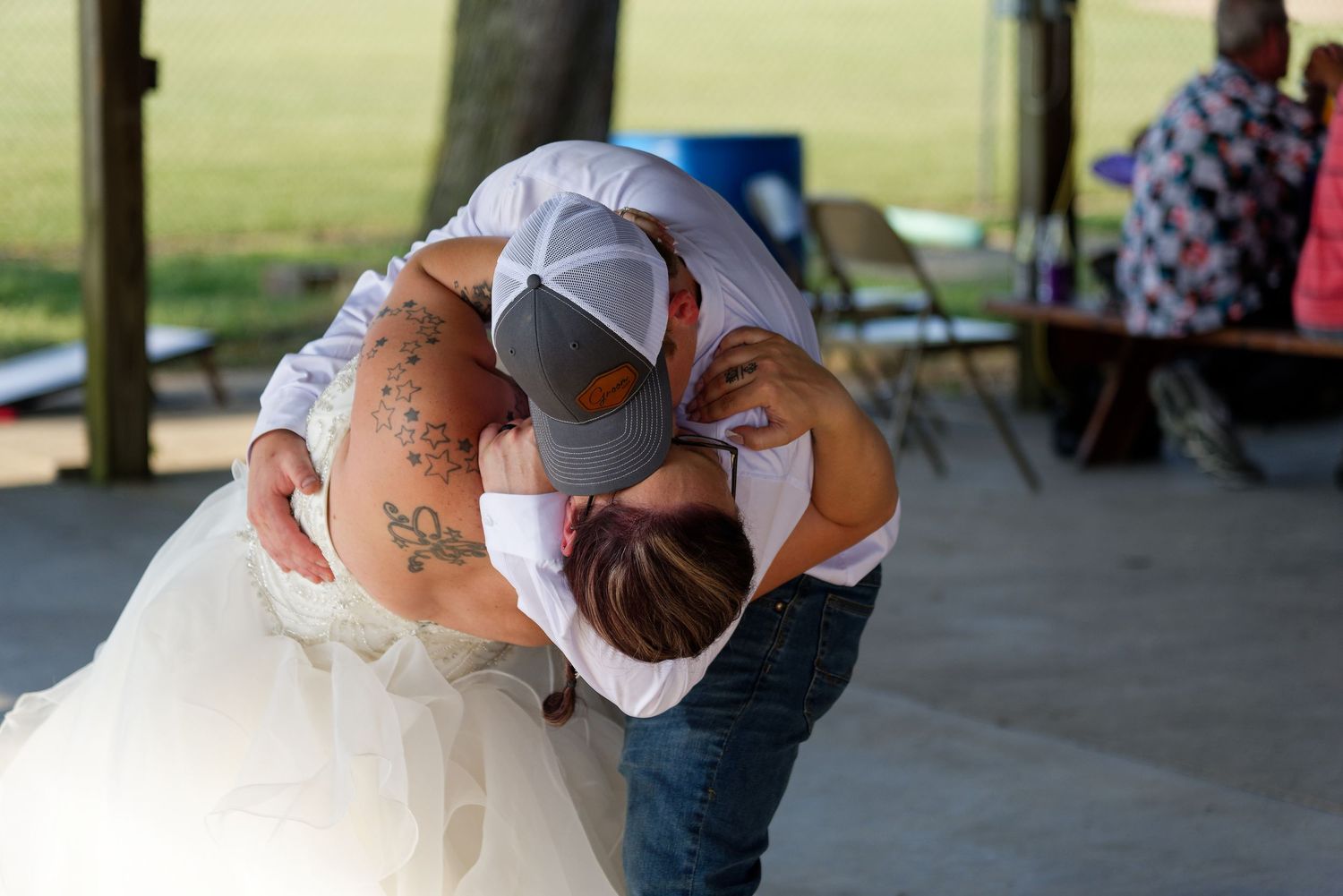 A couple shares a romantic dip while dancing at an outdoor covered venue.